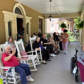 Residents enjoy a sunny day on the porch, sharing moments and smiles.