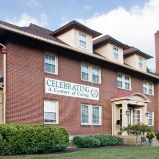 A brick residential building with a sign celebrating a century of caring.