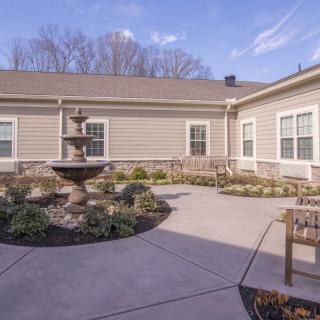 A peaceful courtyard with a central fountain, surrounded by landscaping and benches.