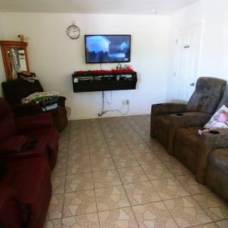A cozy living room with sofas, a wall-mounted TV, and tiled flooring.