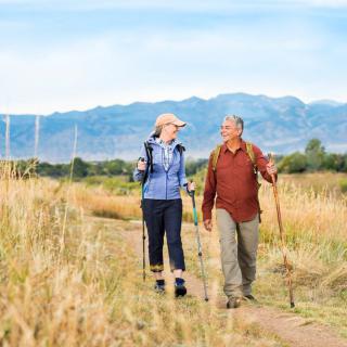 A couple enjoying a hike on a scenic trail with mountains in the background.