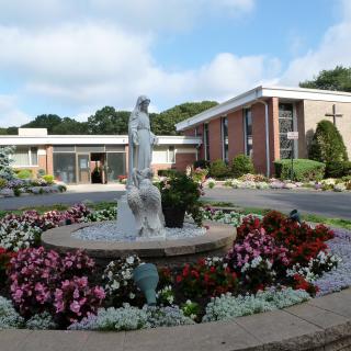 A serene garden with a statue fountain in front of a church building.