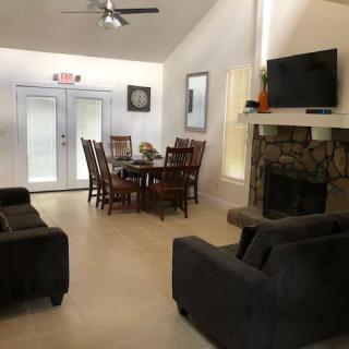 A cozy living and dining space with a fireplace, featuring comfortable sofas, a television, and a dining table surrounded by chairs.