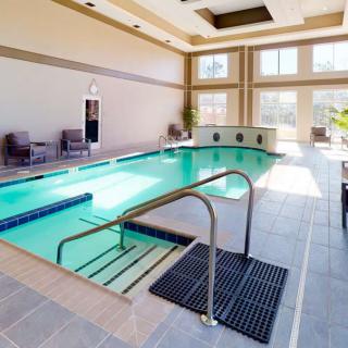 An elegant indoor swimming pool with ample natural lighting and comfortable seating.