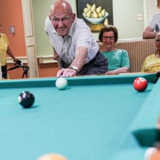 A group of senior citizens enjoying a game of billiards indoors.