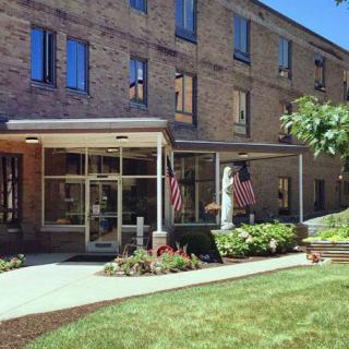 Entrance of a brick building with flags and well-maintained landscaping.