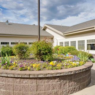 A beautifully landscaped garden featuring a circular flower bed, surrounded by a modern building.