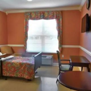 A cozy room featuring a bed, a window with curtains, and a table with chairs.