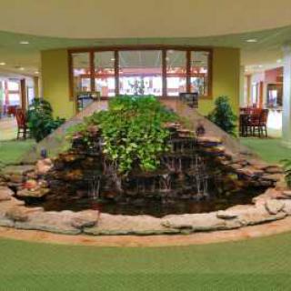 An indoor lobby featuring a decorative water fountain surrounded by plants.