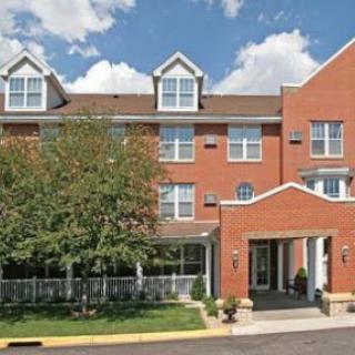 A view of a three-story brick hotel with a welcoming entrance under a partly cloudy sky.