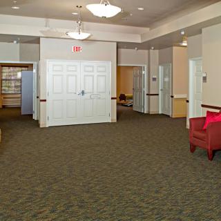A spacious lobby with carpeted flooring, featuring comfortable seating and bright lighting.