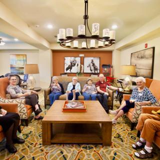 A group of seniors sitting in a cozy living room setting, socializing and relaxing together.