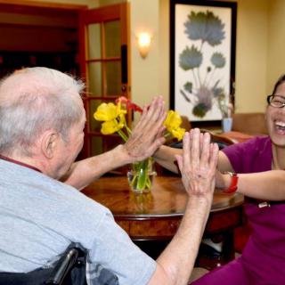 A joyful interaction between a caregiver and an elderly person in a nursing home setting.
