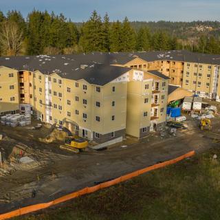 Aerial view of an apartment building under construction surrounded by trees.