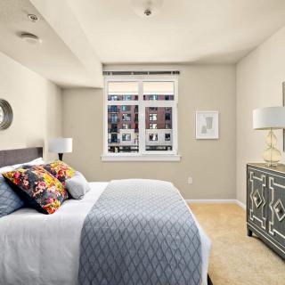 A well-lit bedroom with a comfortable bed, colorful pillows, and stylish decor.