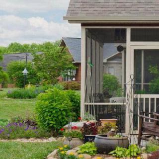 A serene backyard garden with a screened porch and lush greenery.