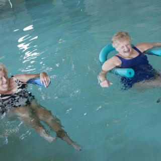 Two women enjoying water aerobics in a swimming pool.