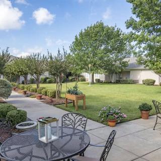 A serene backyard garden with a patio, outdoor furniture, and lush greenery.