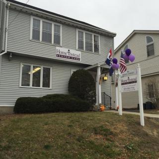 A house with a 'for sale' sign, decorated with balloons and an American flag.