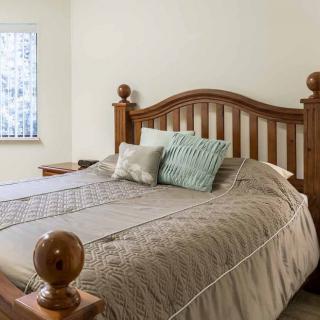 A cozy bedroom featuring a bed with a wooden headboard and decorative pillows.