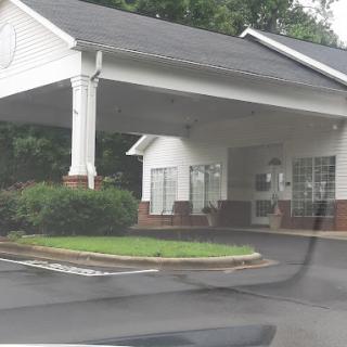 A view of a hotel entrance with a covered canopy and landscaped area.