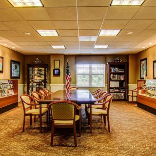 A conference room with a central table, chairs, bookshelves, and decorative elements.