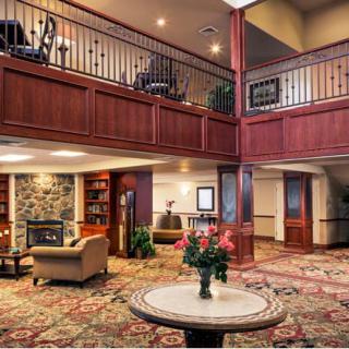 A cozy hotel lobby featuring a fireplace, elegant wood paneling, and comfortable seating.