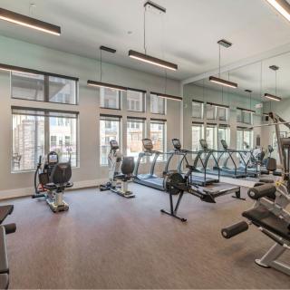 A modern gym with various exercise equipment and large windows.