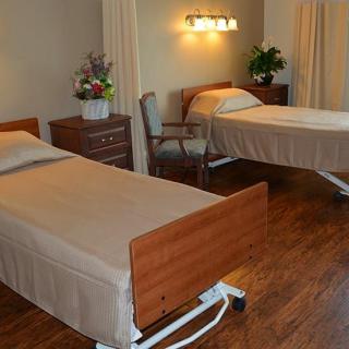 A hospital room with two single beds and wooden flooring.