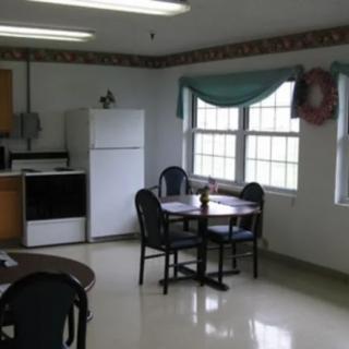 A kitchen and dining area with a round table, chairs, and large windows.