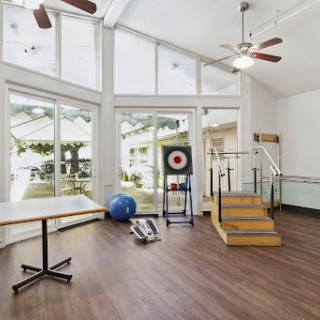 A spacious exercise room with large windows, featuring workout equipment and a welcoming atmosphere.