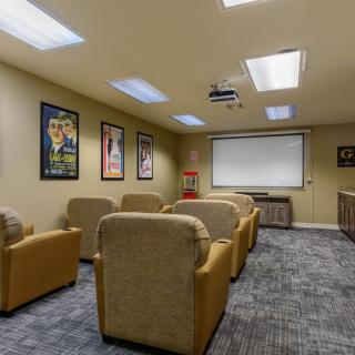 A cozy home theater with comfortable seating and a projector screen, decorated with movie posters.