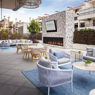 A modern outdoor patio featuring cozy seating arrangements and a large fireplace, perfect for relaxation and entertainment.