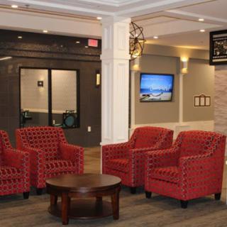 A modern lobby featuring red upholstered chairs and a central coffee table.