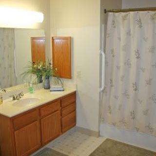 A clean and organized bathroom with a sink, mirror, and shower curtain.