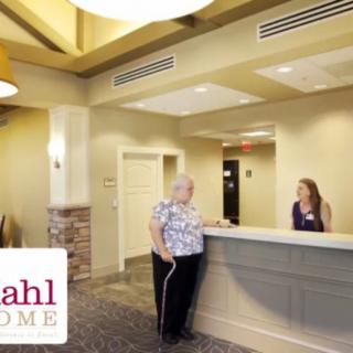 A reception area with two people interacting at the front desk.