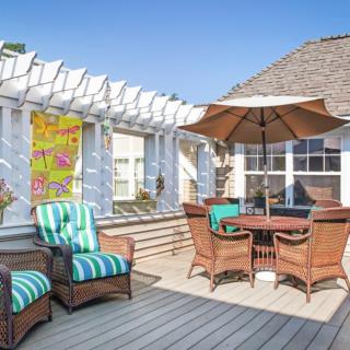 A sunny outdoor deck with wicker furniture and a large umbrella.