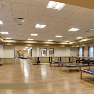 A spacious fitness center with ping pong tables and wood flooring.