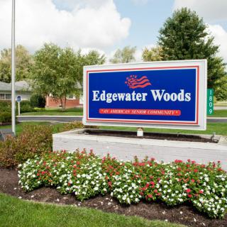 A sign for Edgewater Woods surrounded by a landscaped garden with flowers.