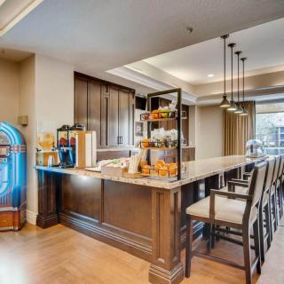 A modern kitchen bar area featuring a countertop with stools, elegant lighting, and a jukebox for entertainment.