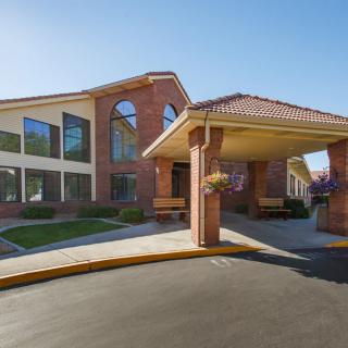 The image showcases a brick building with large windows and an entrance featuring a covered walkway.