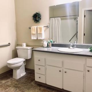 A clean and well-organized bathroom with a sink, toilet, and mirror.