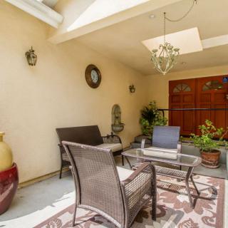 A cozy outdoor patio area with rattan furniture, decorative plants, and a skylight.