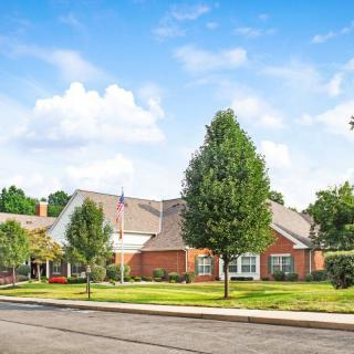 A suburban residential building surrounded by trees under a blue sky.