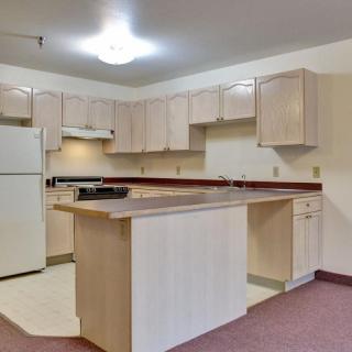 A modern kitchen interior with light wood cabinets and appliances.