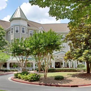 A beautiful building surrounded by lush greenery and trees on a sunny day.
