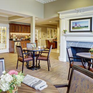 A cozy dining area with tables, chairs, and a fireplace, elegantly decorated with flowers.