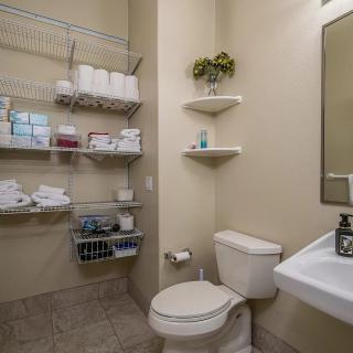 A well-organized bathroom featuring wall shelves stocked with toiletries and towels.