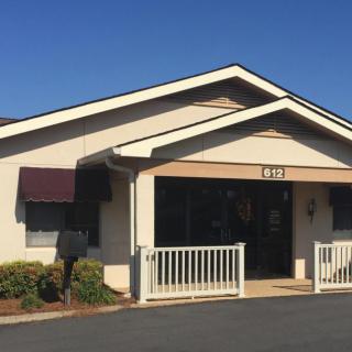 A small building with a front entrance and awnings on a clear day.