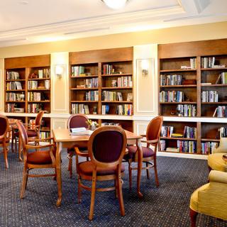 A cozy library interior with bookshelves, tables, and chairs for reading.